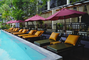 Guest relaxing on a private balcony overlooking the pool at Phuvaree Resort, surrounded by tropical greenery — capturing the calm and warmth of a luxury tropical escape.
