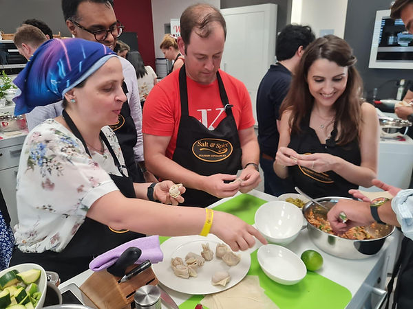 Corporate team-building participants preparing food together during a hands-on Salt & Spice cooking workshop in Luxembourg.