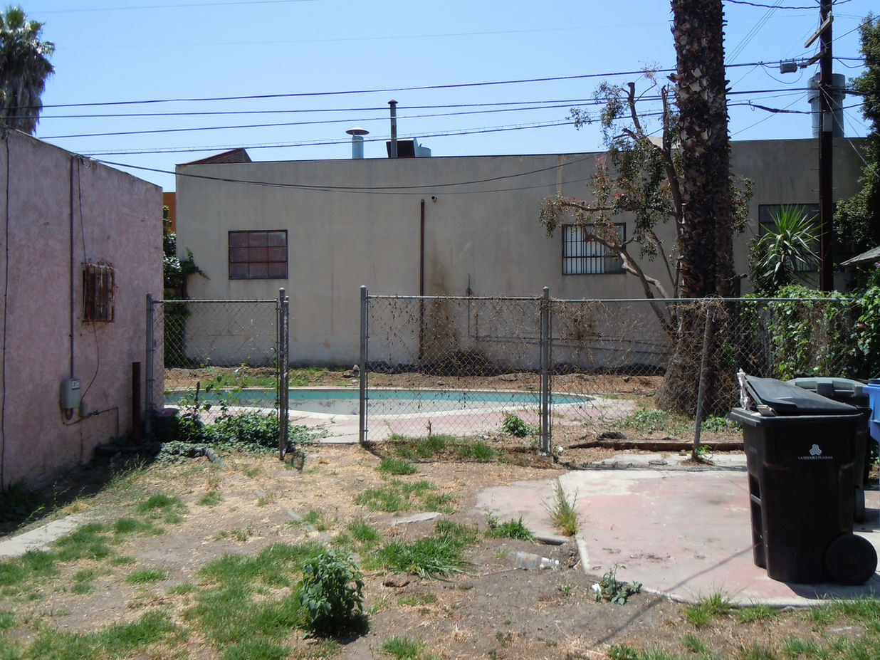 Unkempt landscaping, worn out fencing around empty pool
