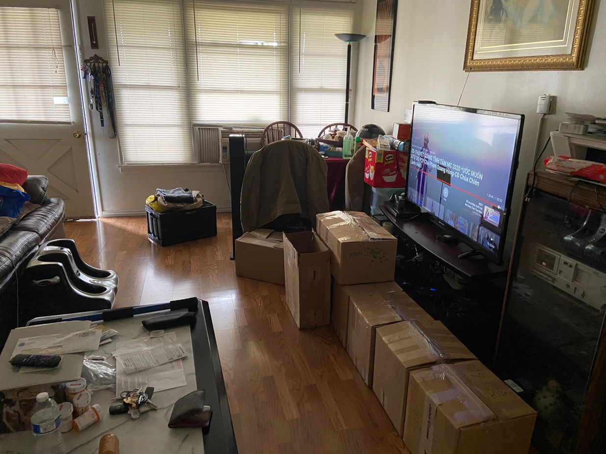 Living room with wooden floors. Tv and moving boxes with furniture
