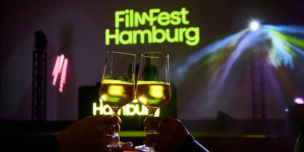 Zwei Weingläser vor dem leuchtenden FilmFest-Hamburg-Logo bei einer Festivalveranstaltung.