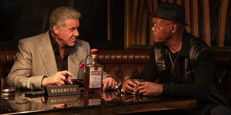 Sylvester Stallone und Samuel L. Jackson sitzen sich in einer Bar gegenüber, trinken Whiskey und sprechen miteinander – Szene aus „Tulsa King“.