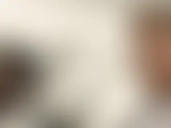 Zwei Rennfahrer in weißen Overalls stehen nebeneinander auf einer Rennstrecke und blicken konzentriert nach vorn. Im Hintergrund sind Tribünen und Teile einer Formel-1-Strecke zu sehen. Die Szene stammt aus dem Film „F1 – Der Film“.