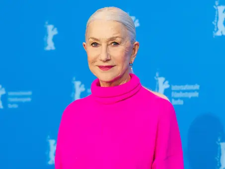 Helen Mirren in pinkfarbenem Rollkragenpullover vor blauem Berlinale-Hintergrund.