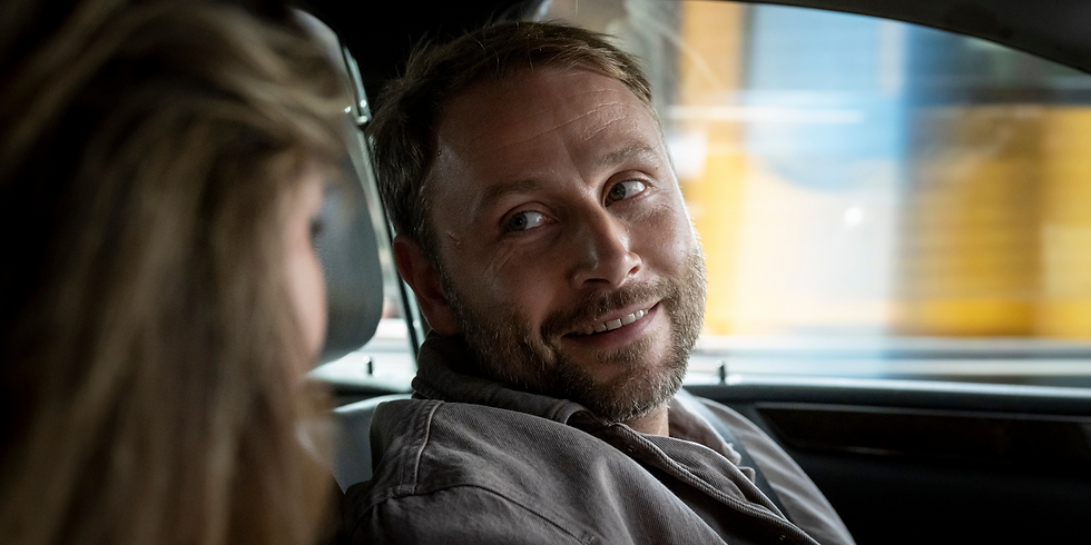 Szene aus „Es geht um Luis“: Ein Mann im Auto lächelt eine neben ihm sitzende Frau an.