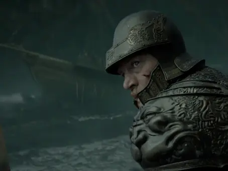 Szenenbild aus der dritten Staffel von „House of the Dragon“: Ein gepanzerter Krieger blickt in einer dunklen, nebligen Umgebung über seine Schulter. Er trägt einen Helm und eine kunstvoll verzierte Rüstung mit einem drachenähnlichen Relief auf der Schulterpartie.
