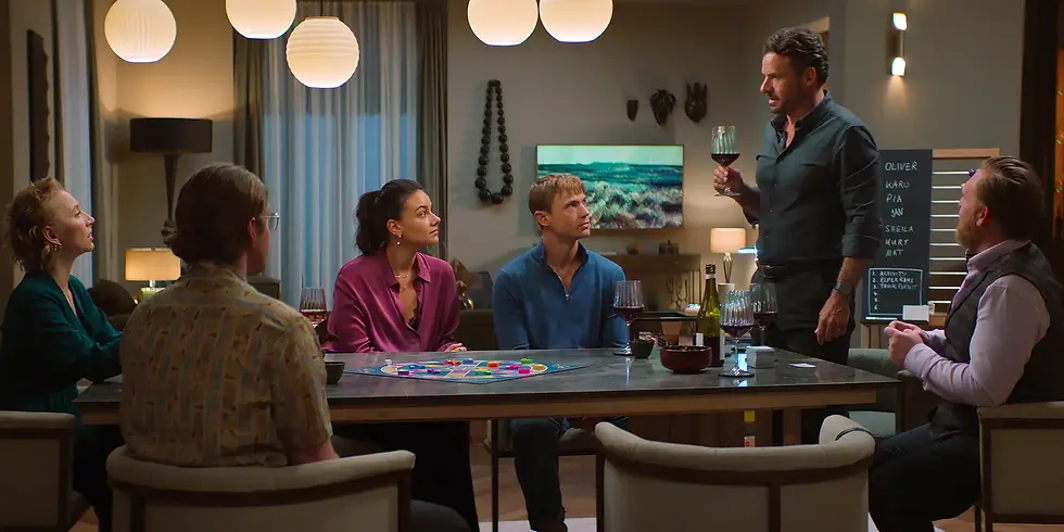 Anna Maria Mühe, Max Bretschneider, Janina Uhse, Dennis Mojen, Stephan Luca und Axel Stein sitzen beziehungsweise stehen bei einem gemeinsamen Spieleabend um einen Tisch im Film „Spieleabend“.