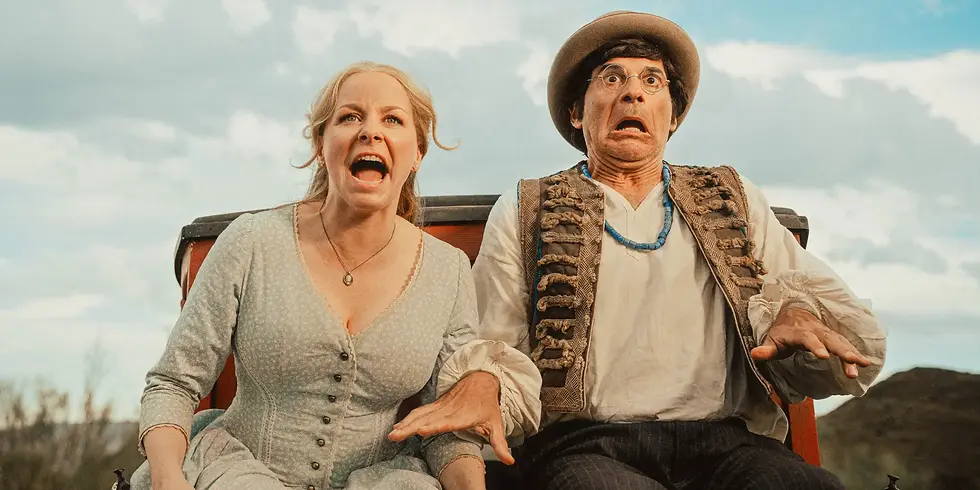 Eine Frau und ein Mann sitzen erschrocken auf einer Kutsche und blicken nach vorne – humorvolle Szene aus „Das Kanu des Manitu“.