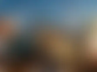 Eine Frau balanciert auf dem neu enthüllten Eingangsportal eines historischen Zirkus in der ARD-Serie „Der Circus – Welt der Träume“. Unter ihr blickt eine Menschenmenge nach oben, während im Hintergrund Zirkuszelte, Fahnen und zwei große Heißluftballons zu sehen sind.