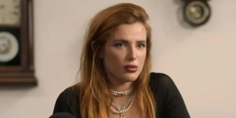 Bella Thorne sitzt in einem Innenraum und blickt während eines Gesprächs zur Seite. Sie trägt ein schwarzes Oberteil und mehrere Halsketten.
