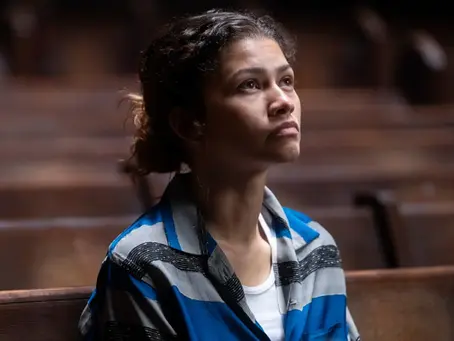 Zendaya als Rue Bennett in „Euphoria“, sitzt allein auf einer Kirchenbank, blickt nach oben, ruhige und nachdenkliche Stimmung in warmem Licht.