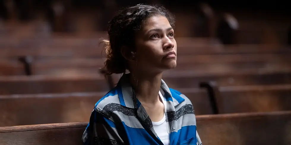 Zendaya als Rue Bennett in „Euphoria“, sitzt allein auf einer Kirchenbank, blickt nach oben, ruhige und nachdenkliche Stimmung in warmem Licht.