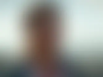 Eleven aus „Stranger Things“ steht im Freien vor einer hügeligen Landschaft und blickt ernst in die Ferne.