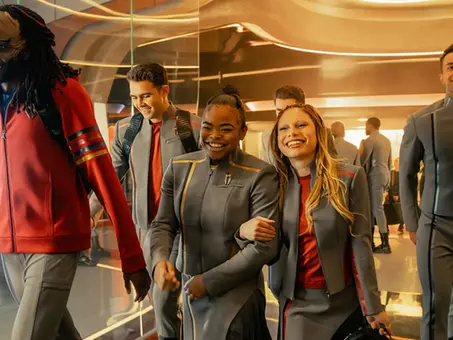 Szene aus „Star Trek: Starfleet Academy“: Eine Gruppe junger Kadetten in grauen Uniformen läuft lachend durch die futuristische Sternenflottenakademie.