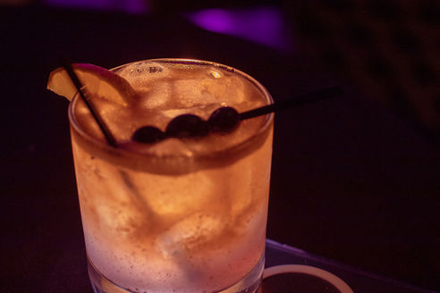 Cocktail in rocks glass with lemon slice and cherries.