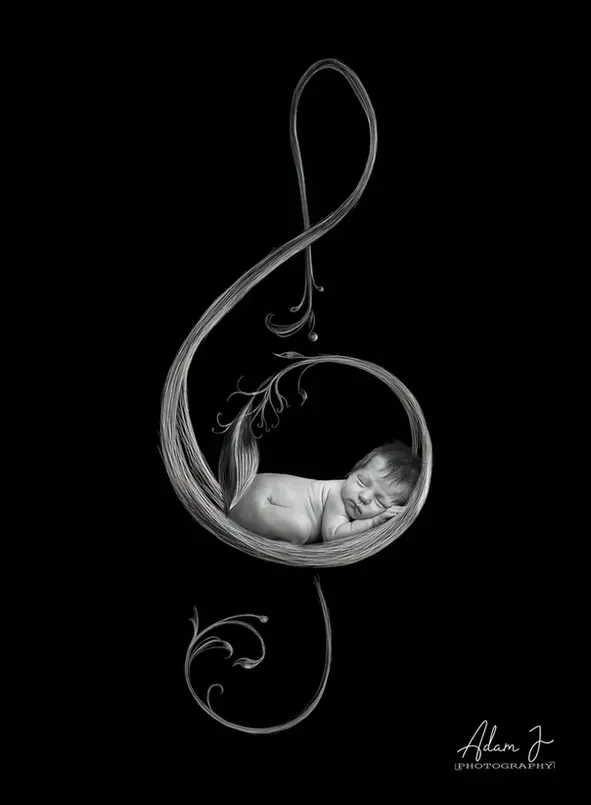 Newborn sleeping inside a decorative treble clef musical symbol
