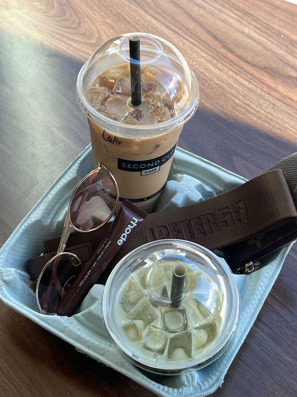 Brown Christian keychain from The Found Keychain Collection styled on a beverage tray with a latte, matcha, sunglasses, and brown lip gloss — an aesthetic setup appealing to fashion-forward young adults in Montreal and Canada who value faith, Scripture, and Christian lifestyle accessories.