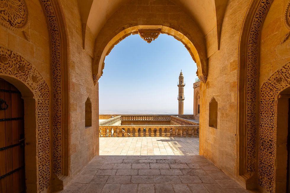 View of Mardin’s historic stone architecture with an arch framing the Mesopotamian valley and a minaret in the distance.