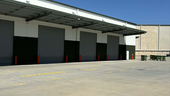 External industrial repaint of a large warehouse facility in Yatala, QLD, featuring freshly applied protective coatings on precast concrete panels