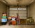 Sims 4 Storage Wars CC set preview featuring old armchair, storage boxes, rug, CD player, dusty wall art, and cobweb overlays in a grungy garage scene
