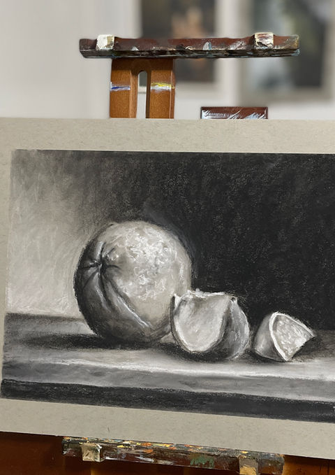 Charcoal still life drawing on easel showing sphere and geometric forms