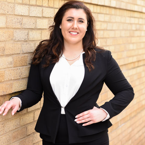 a professional headshot of a woman against a brick wall
