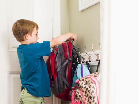 Child hanging up a coat at the front door