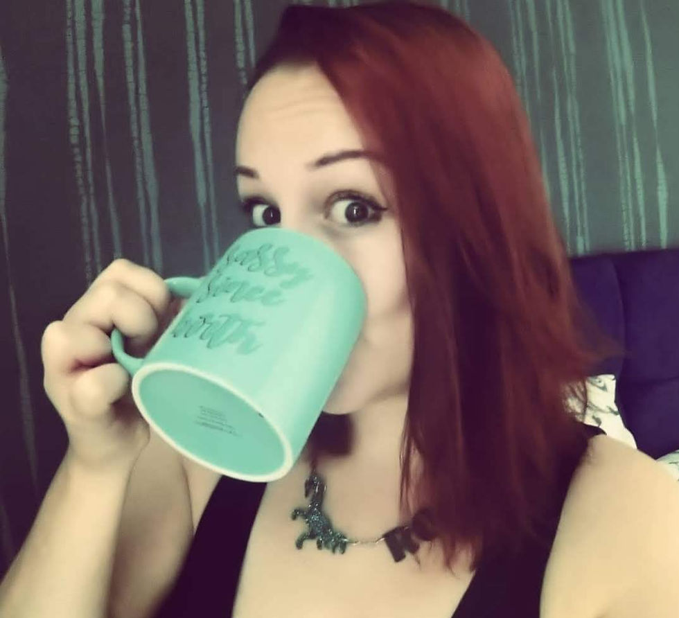 It's me! I have red hair in the photo (it is currently dark), and I'm weraring anecklace that says ROAR and has a dinosaur on. I'm drinking coffee from a light green mug.