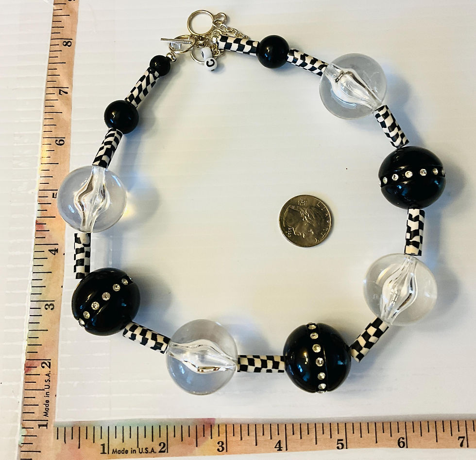 Thumbnail: Black and white beaded necklace with clear and black beads near a coin.