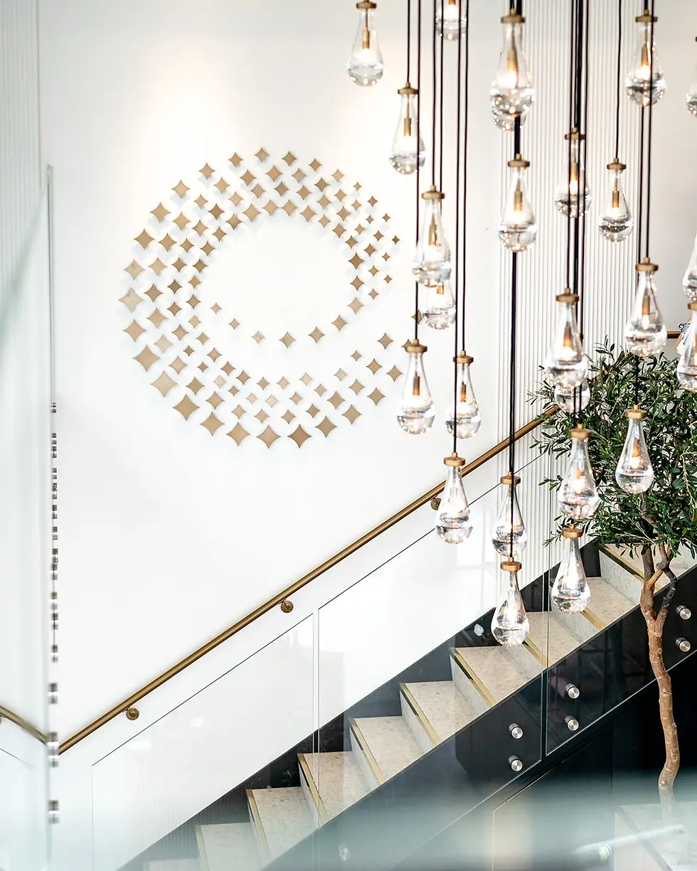 Elegant staircase and chandelier lighting inside Evolve Sparkling House with gold circular wall design