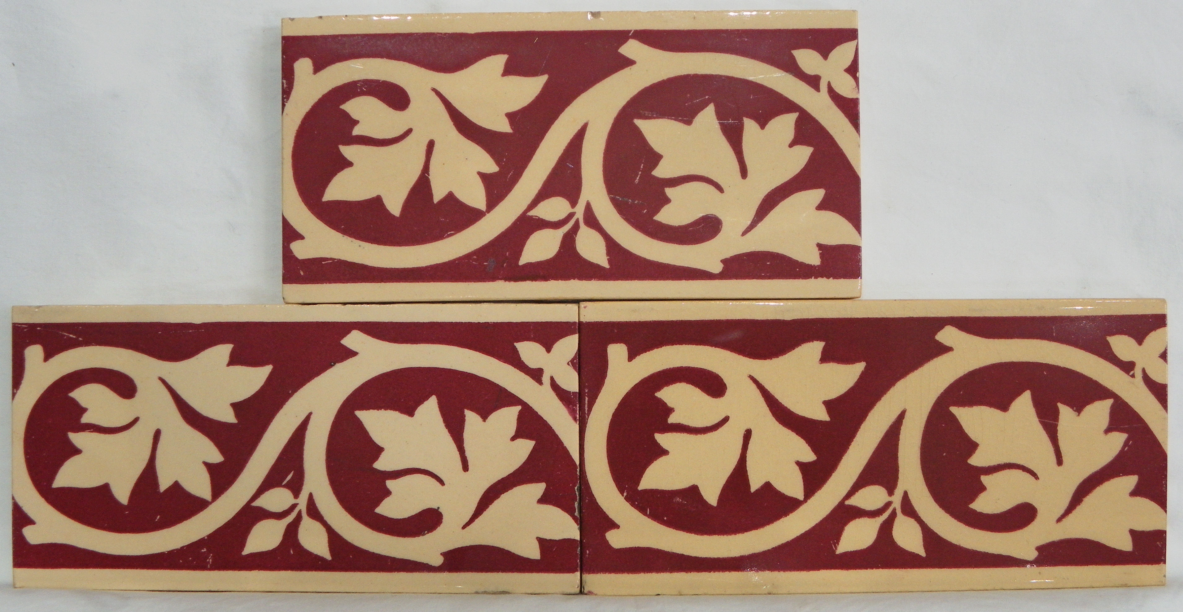 A collection of 3 foliate scroll tiles - red and buff
