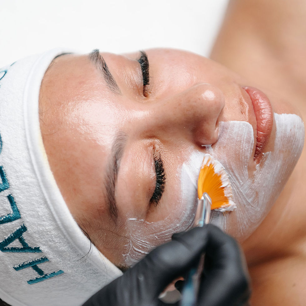 Hale & Hush Charcoal Clarifying mask being applied to a woman's face with a fan brush.