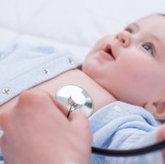 a baby laying down with their sleeper unbuttoned so a doctor can place a stethoscope on their chest