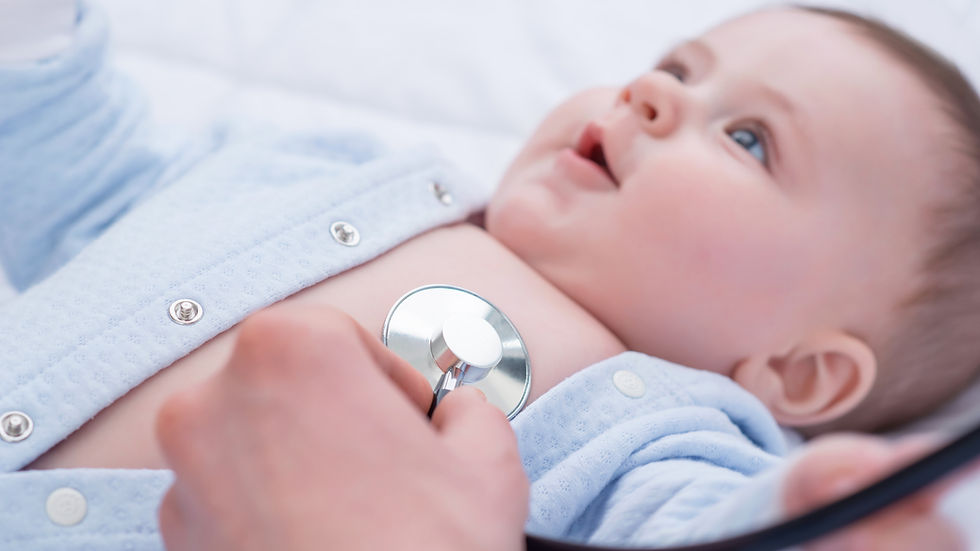 Baby in a blue outfit having chest examined with a stethoscope. 