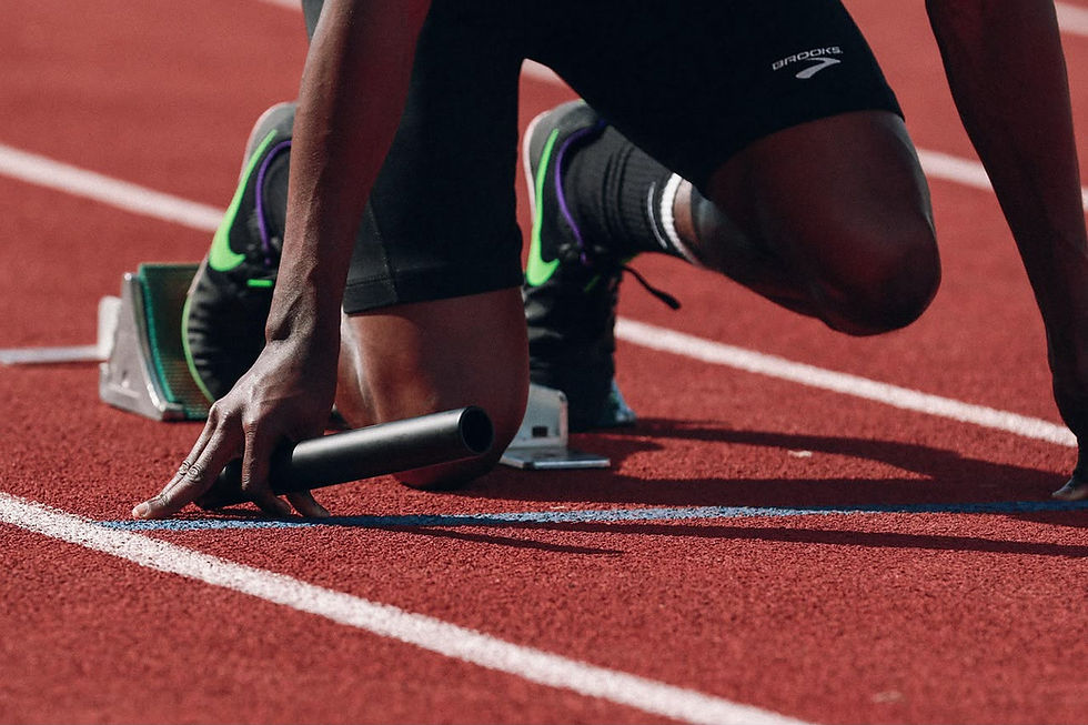 Image the legs and hands of a relay runner in the starting blocks