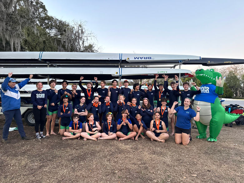 SCAR athletes and coaches pose with medals beside the team gator mascot.