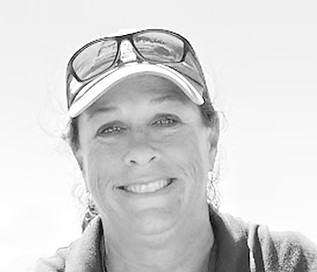 Smiling rowing head coach Michelle Hill wearing a visor and sunglasses on her head.