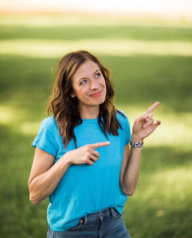 Emily in a blue shirt looking upwards and pointing to the right