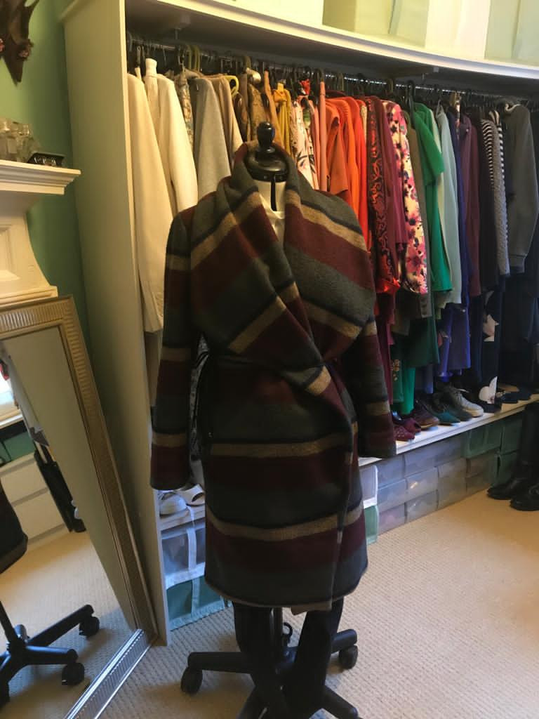 A Multicoloured wraparound coat on a mannequin in front of a wardrobe