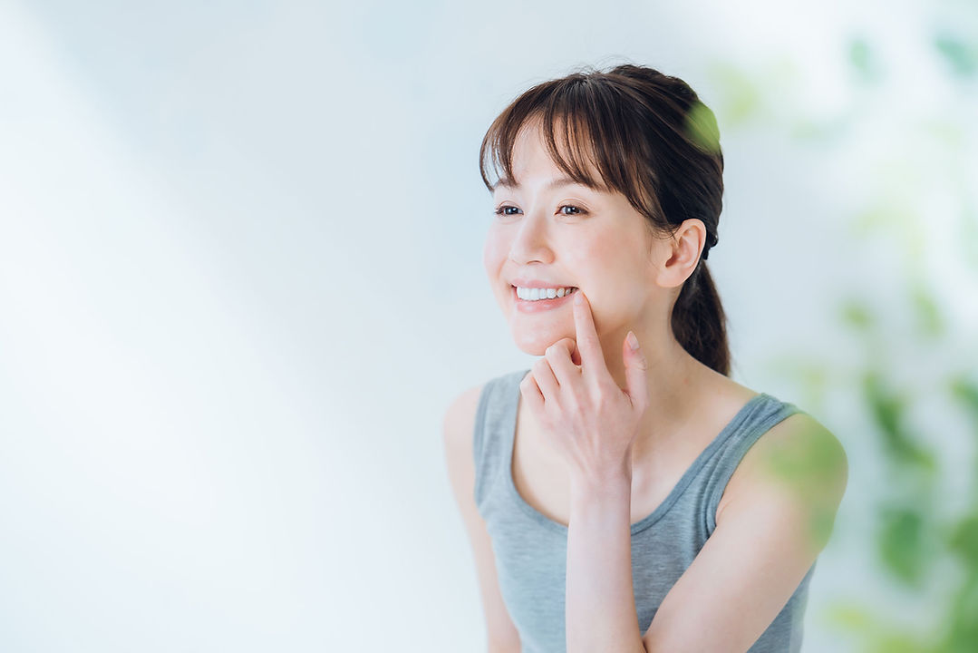 口元を指を置いて笑顔の女性