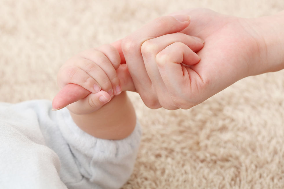 お母さんの指を握る赤ちゃんの手