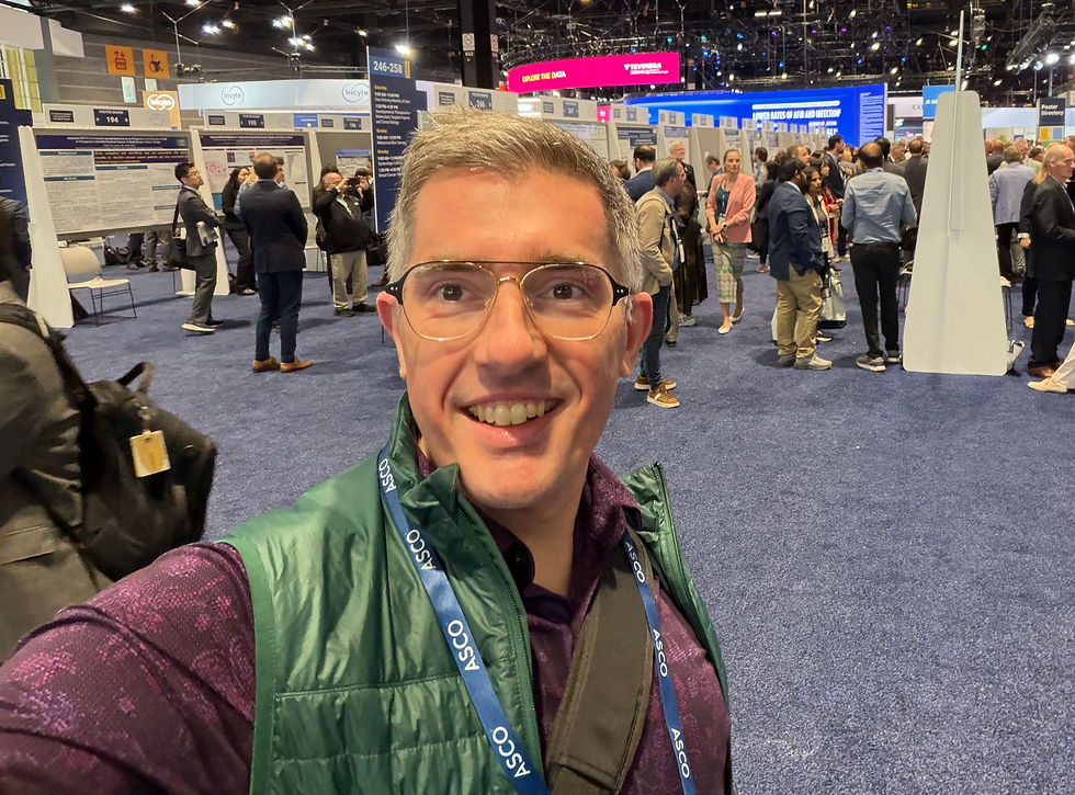 Smiling man takes a selfie at a busy medical conference poster hall, with attendees and research posters behind him.