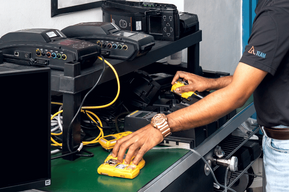 A person repairing or testing electronic equipment on a workbench.