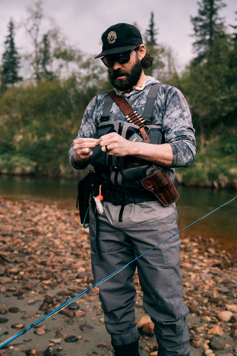 fisherman on a heli fishing in alaska tying a fly fishing tie