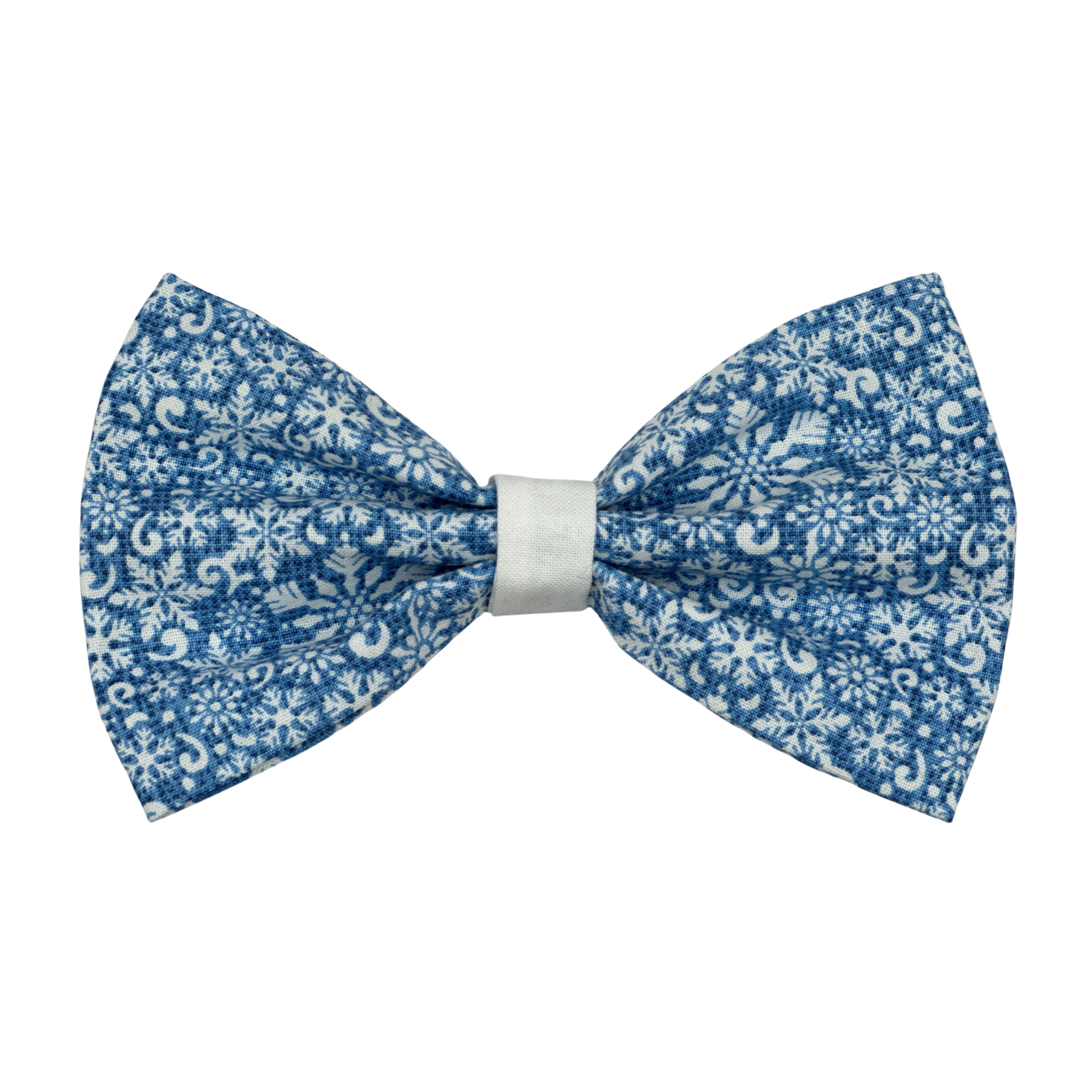 Light blue dog bow tie with intricate white snowflake and swirl patterns and a white center band.