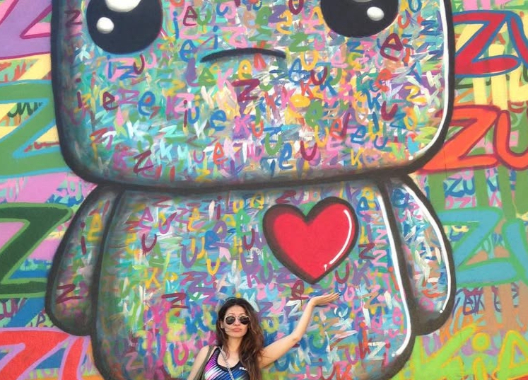 Dariya Repina standing by a colorful mural in Brooklyn, New York City.