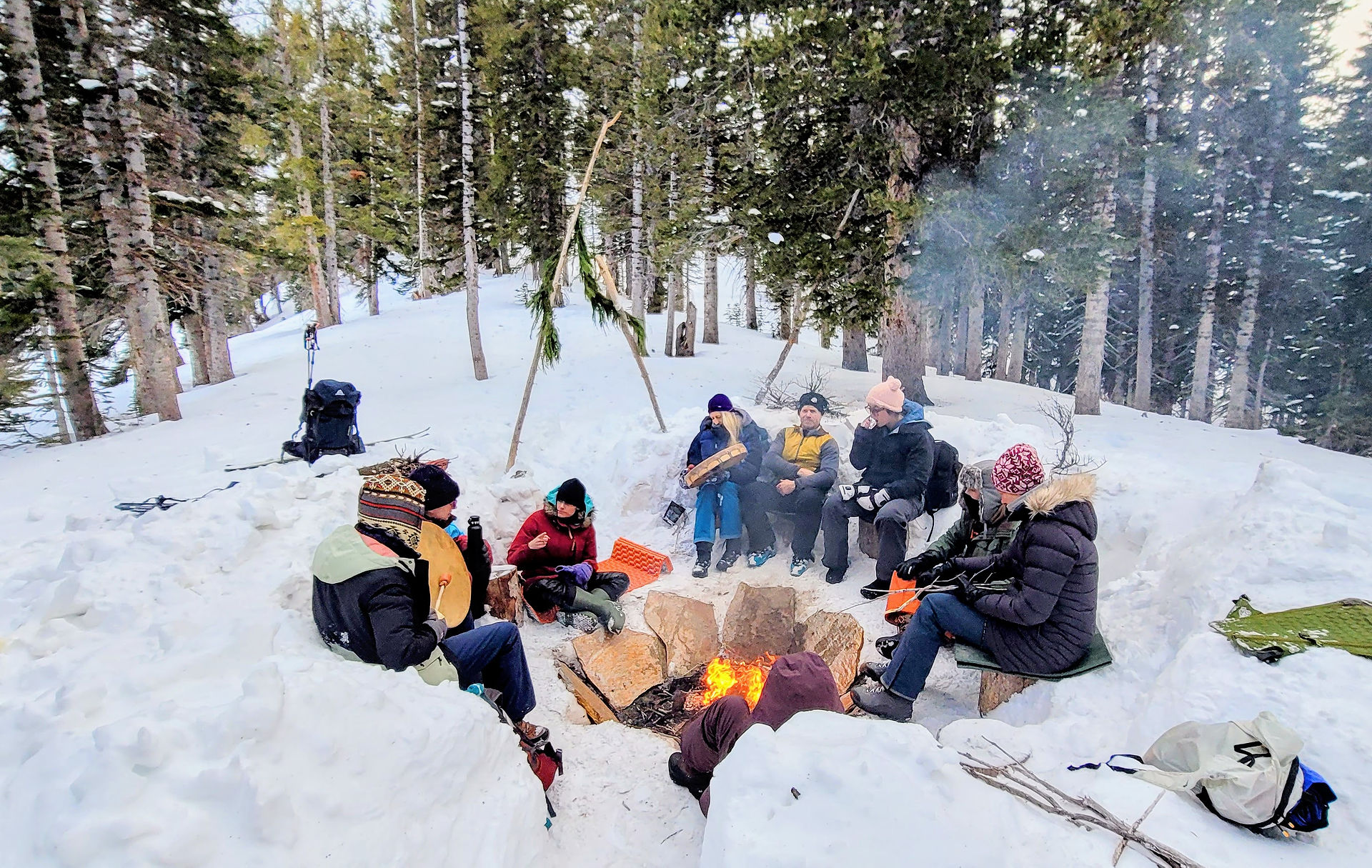 a community of people sit around the fire pit with alot of snow