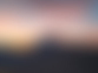 Mountain peak at sunset with vibrant orange and pink clouds. Rugged terrain in the foreground creates a serene, majestic atmosphere.