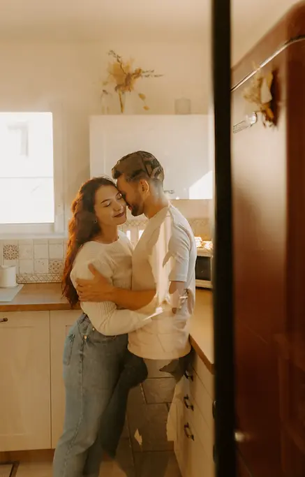 couple s'enlaçant dans la cuisine la femme a les yeux fermés