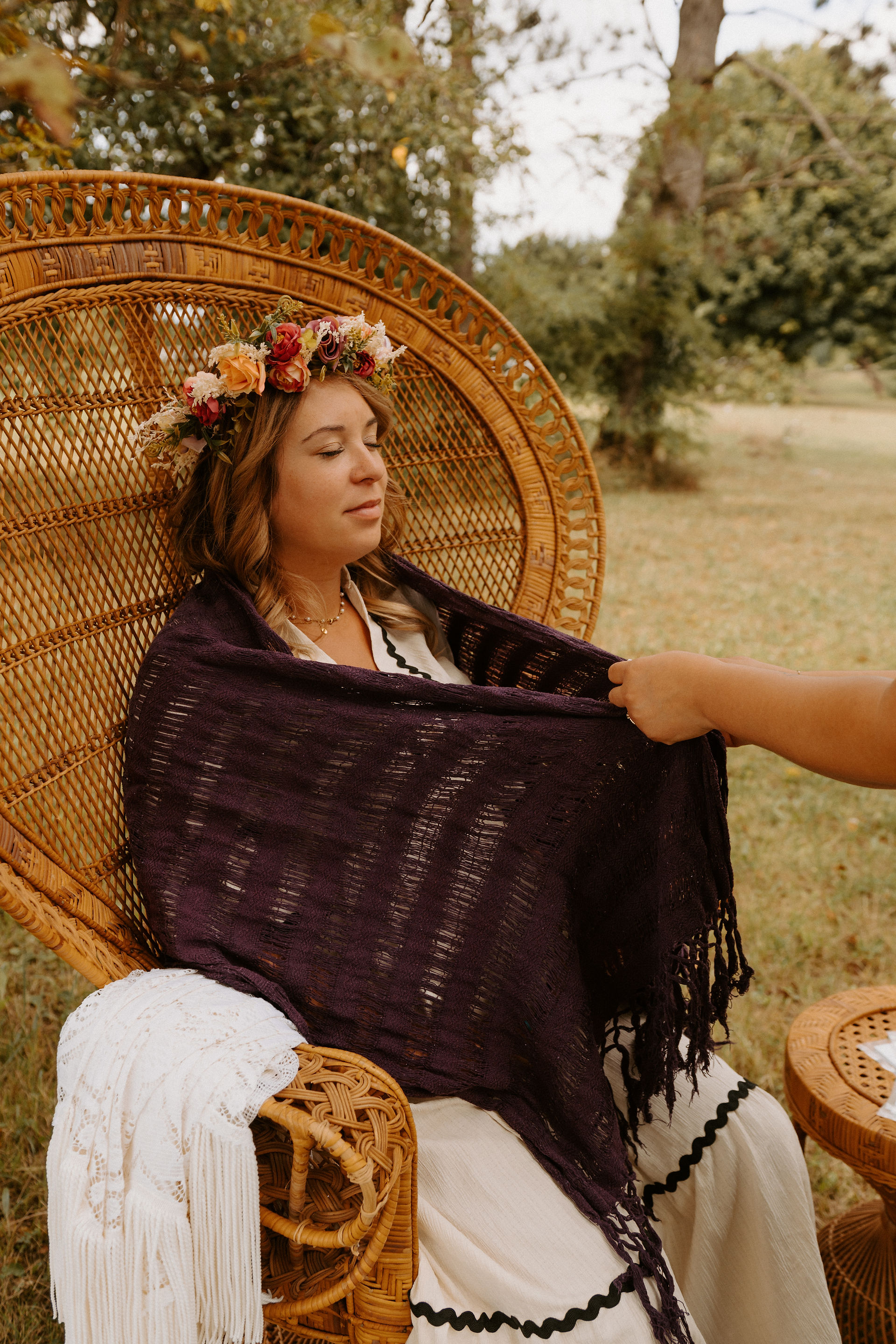 Femme dans une chaise en rotin, portant une couronne de fleurs. Le Mama Blessing: célébrer la femme.